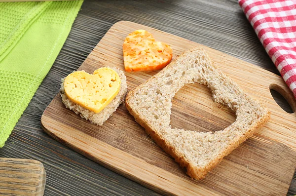 Bread slice with cut in shape of heart and cheese on table close up — Stock Photo, Image