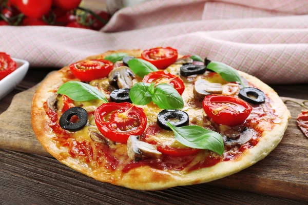 Gustosa pizza con verdure e basilico in tavola da vicino — Foto Stock