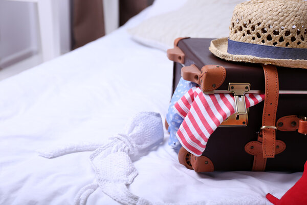 Чемодан с одеждой на кровати в номере
