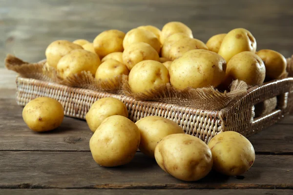 Nieuwe aardappelen in lade op houten achtergrond — Stockfoto