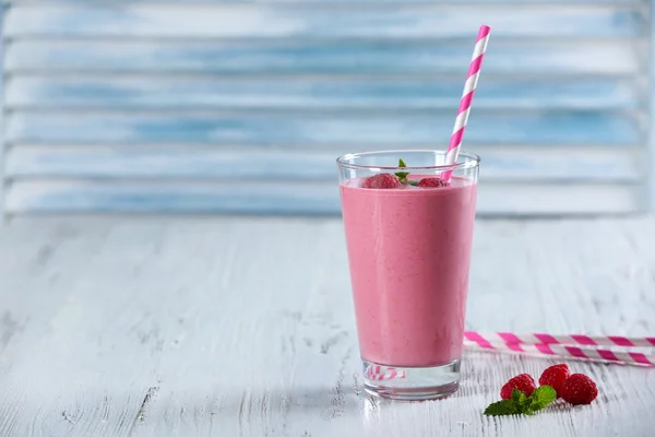 Vaso de batido de leche de frambuesa con bayas sobre fondo de madera —  Fotos de Stock