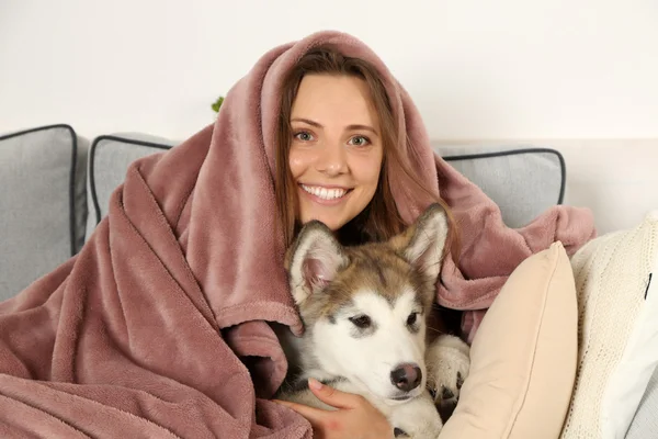 Woman lying with malamute dog on sofa — Stock Photo, Image