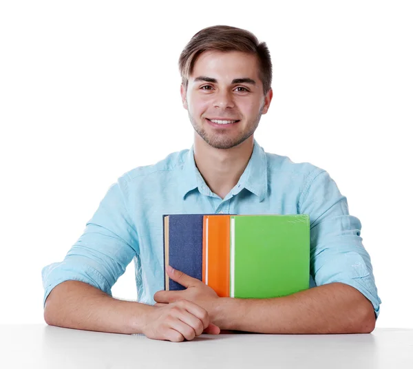 Young man with books at table on white background — Stock Photo, Image