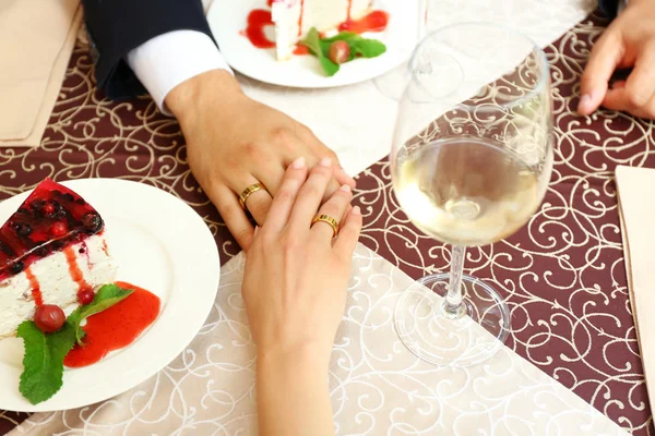 Hands of newlyweds at table in cafe, closeup — Stock Photo, Image