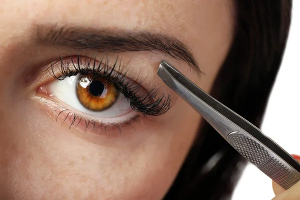 Mujer joven arrancando las cejas con pinzas de cerca — Foto de Stock