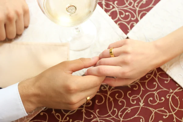 Handen van pasgetrouwden aan tafel — Stockfoto