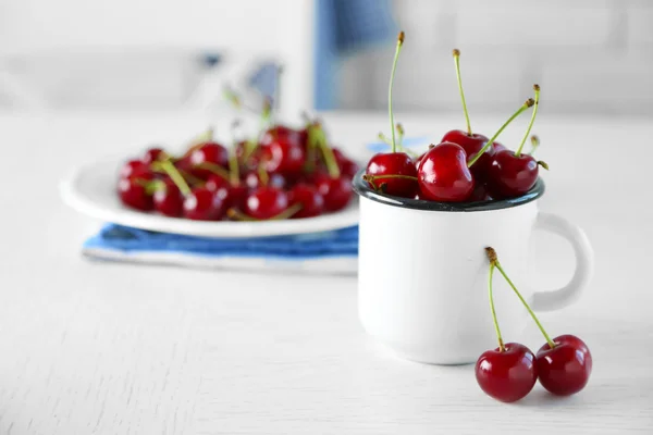 Cherries in mug on table — Stock Photo, Image
