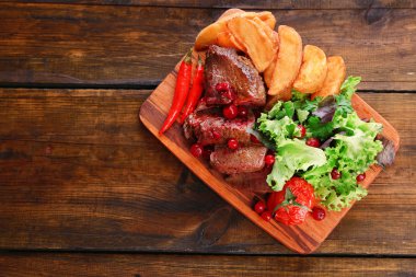 sığır eti ile kızılcık sosu, ahşap arka plan üzerinde kesme tahtası kavrulmuş patates dilimleri