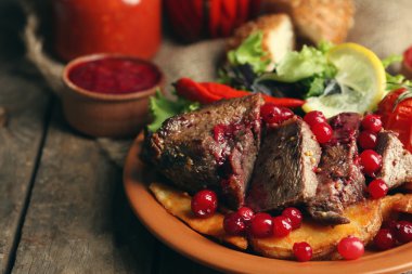 kızılcık sosu, salata ve ahşap arka plan üzerinde plaka üzerinde kavrulmuş sebze ile lezzetli kavrulmuş et