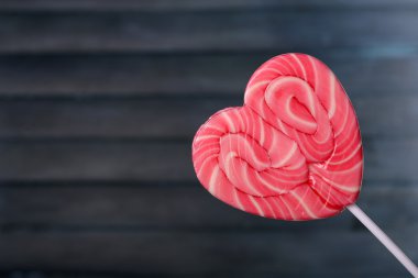 ahşap arka plan üzerinde kalp şeklinde parlak lolipop