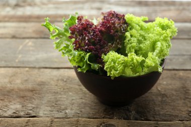 Ahşap masa üzerinde kase taze karışık yeşil salata yakın çekim