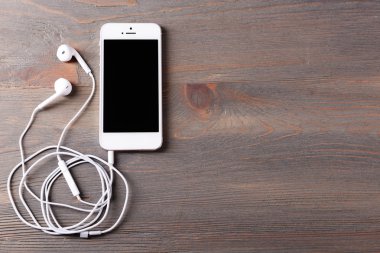 ahşap arka planda cep telefonu ve kulaklık