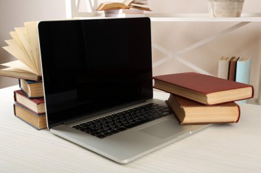 Masada dizüstü bilgisayar ile kitap yığını kapat