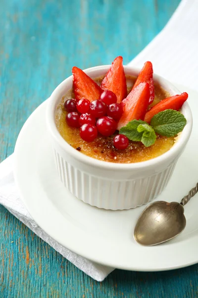 Creme Brulee Dessert mit frischen Erdbeeren und Minzblättern, auf farbigem Holzhintergrund — Stockfoto