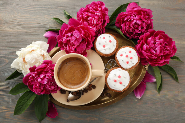 Composition with cup of coffee, muffins and peony flowers on wooden background