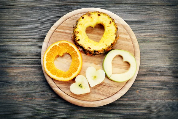 Fruits slices with cut in shape of heart on wooden background — Stock Photo, Image