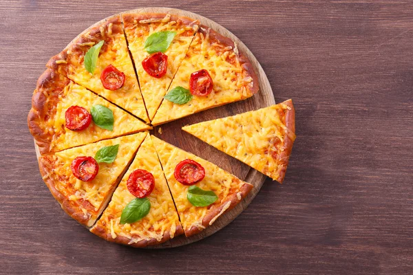 Scheiben leckere Käse-Pizza mit Basilikum und Kirschtomaten auf dem Tisch aus nächster Nähe — Stockfoto