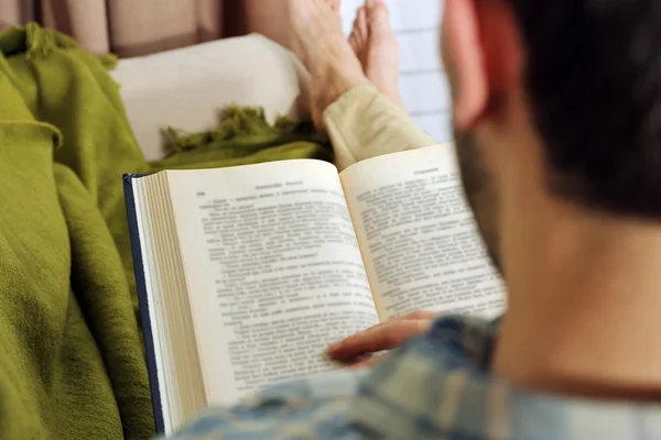Young man reading book on sofa close up — Stock Photo, Image