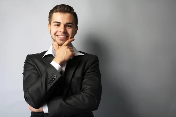 Handsome businessman on gray background — Stock Photo, Image