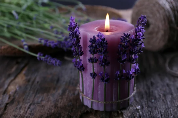 Свеча с цветами лаванды на столе крупным планом — стоковое фото