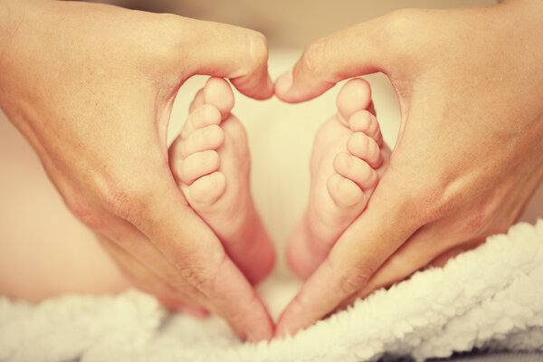 Adult hands holding baby feet, closeup