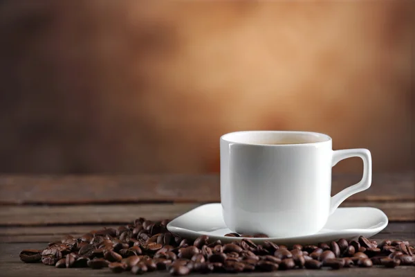 Cup of coffee and beans on blurred background — Stock Photo, Image