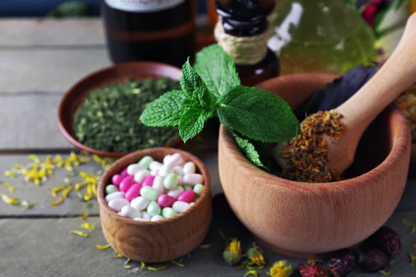 Kruiden, bessen, bloemen en pillen op een houten tafel achtergrond kleur — Stockfoto