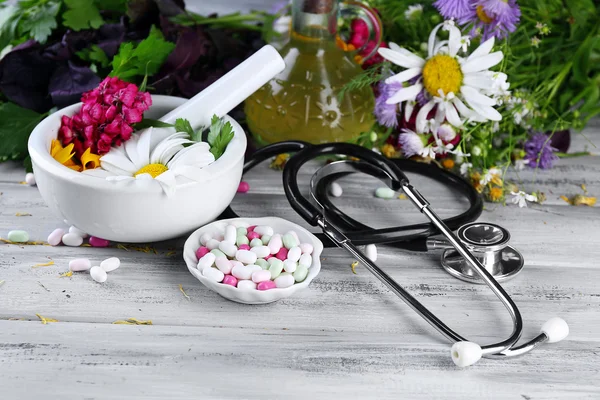 Médecine douce herbes, baies et stéthoscope sur fond de table en bois — Photo