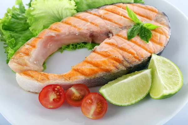 Tasty grilled salmon with tomato and lime on plate close up — Stock Photo, Image