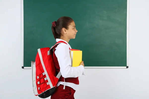 Mooi meisje permanent in de buurt van schoolbord in klas — Stockfoto