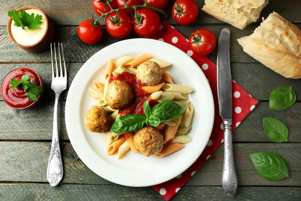 Pasta con albóndigas en plato, sobre fondo de mesa de madera —  Fotos de Stock