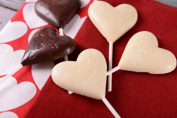 Choklad hjärtformade godis på pinnar på röd Servett, närbild — Stockfoto