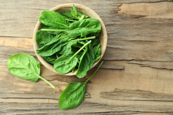 Ciotola di foglie di spinaci freschi su sfondo di legno — Foto Stock