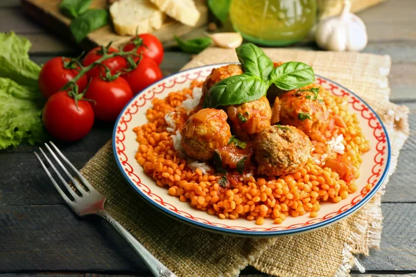 Polpette di carne con lenticchie e salsa di pomodoro, cucchiaio di legno su fondo di legno — Foto Stock