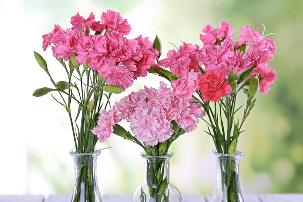 Hermoso ramo de clavel rosa en jarrones sobre fondo brillante — Foto de Stock