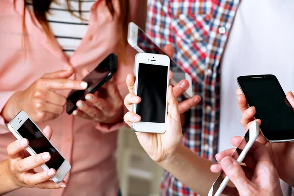 Muitas mãos segurando telefones celulares de perto — Fotografia de Stock