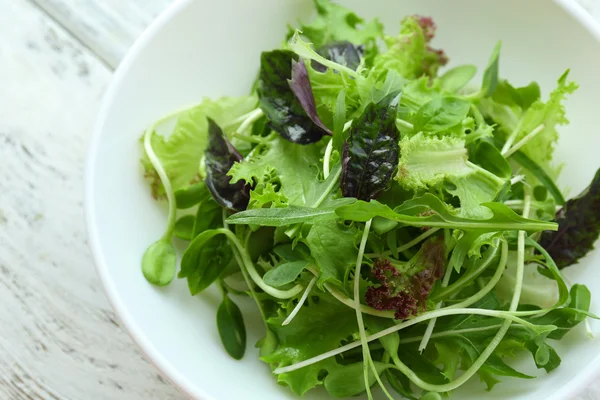 Frischer gemischter grüner Salat in Schüssel in Großaufnahme — Stockfoto