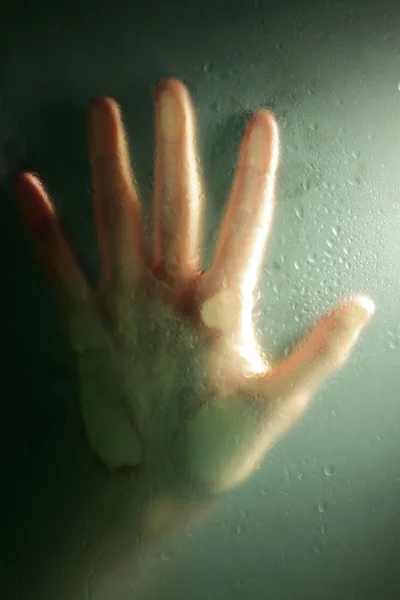 Female hand behind  wet glass, close-up — Stock Photo, Image