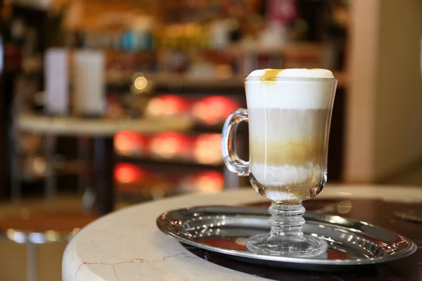 Glass of latte coffee on metal tray in cafe — Stock Photo, Image