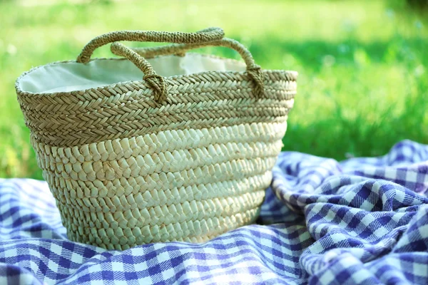 柳条编织的篮子和格子在绿色草地上野餐 — 图库照片
