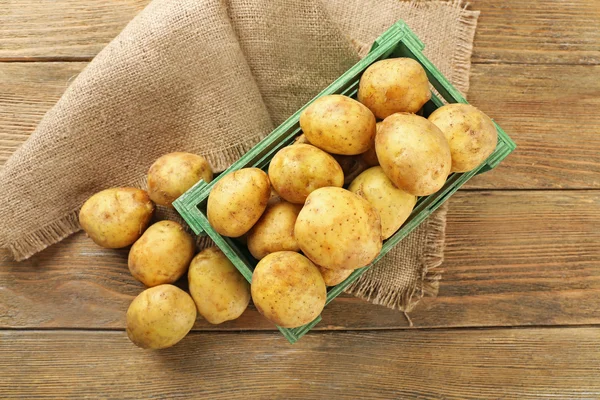 Batatas jovens em caixa na mesa de perto — Fotografia de Stock