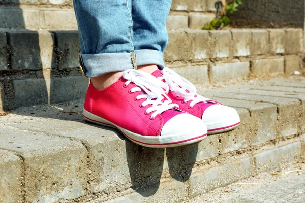 Pies femeninos en zapatos de goma rosa en escaleras de piedra —  Fotos de Stock