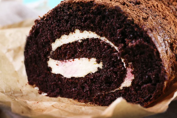 Delicious chocolate roll on parchment, closeup