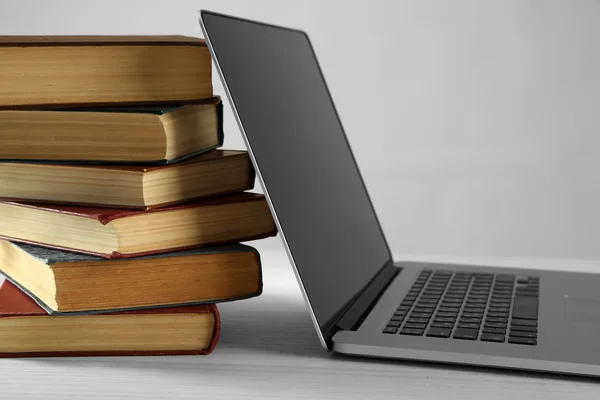 Stapel boeken met laptop op grijze achtergrond — Stockfoto