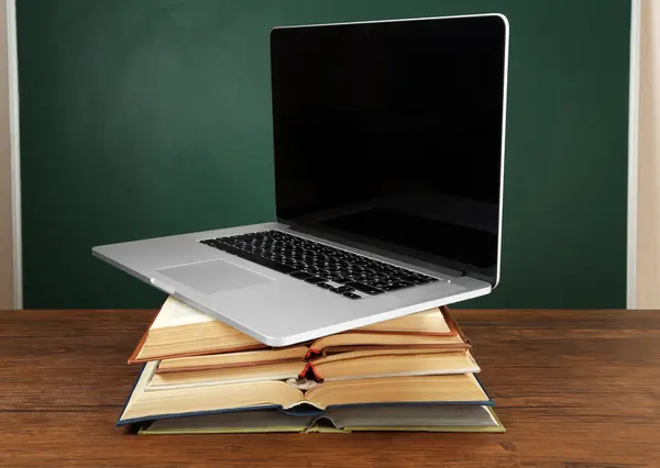 Stapel boeken met laptop op tafel in klas — Stockfoto