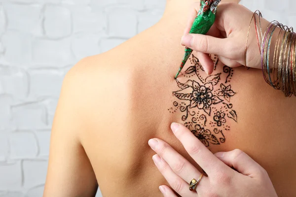 Process of applying Mehendi on female back, on grey wall background — Stock Photo, Image