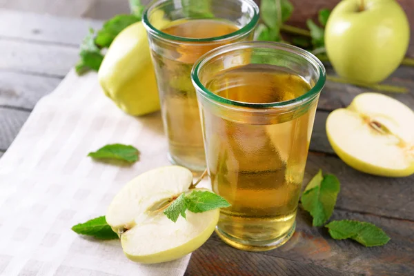 Szklanki soku jabłkowego na drewnianym stole, zbliżenie — Zdjęcie stockowe