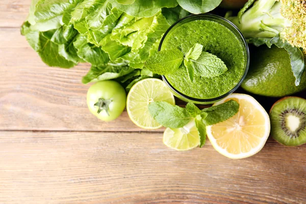 Zelené zdravé šťávy s ovocem a zeleninou na dřevěný stůl zblízka — Stock fotografie