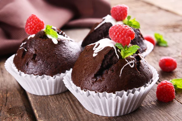 Deliciosos cupcakes de chocolate com bagas e hortelã fresca na mesa de madeira fechar — Fotografia de Stock