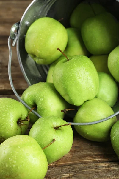 Ripe green apple in metal bucket on wooden table close up — Stock Photo, Image